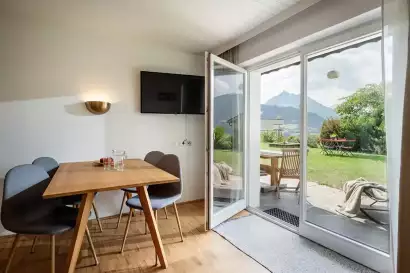 2_tiroler-alpenhof-patsch-fewo-serles_esstisch-mit-gartenzugang_c_hannes-dabernig.webp