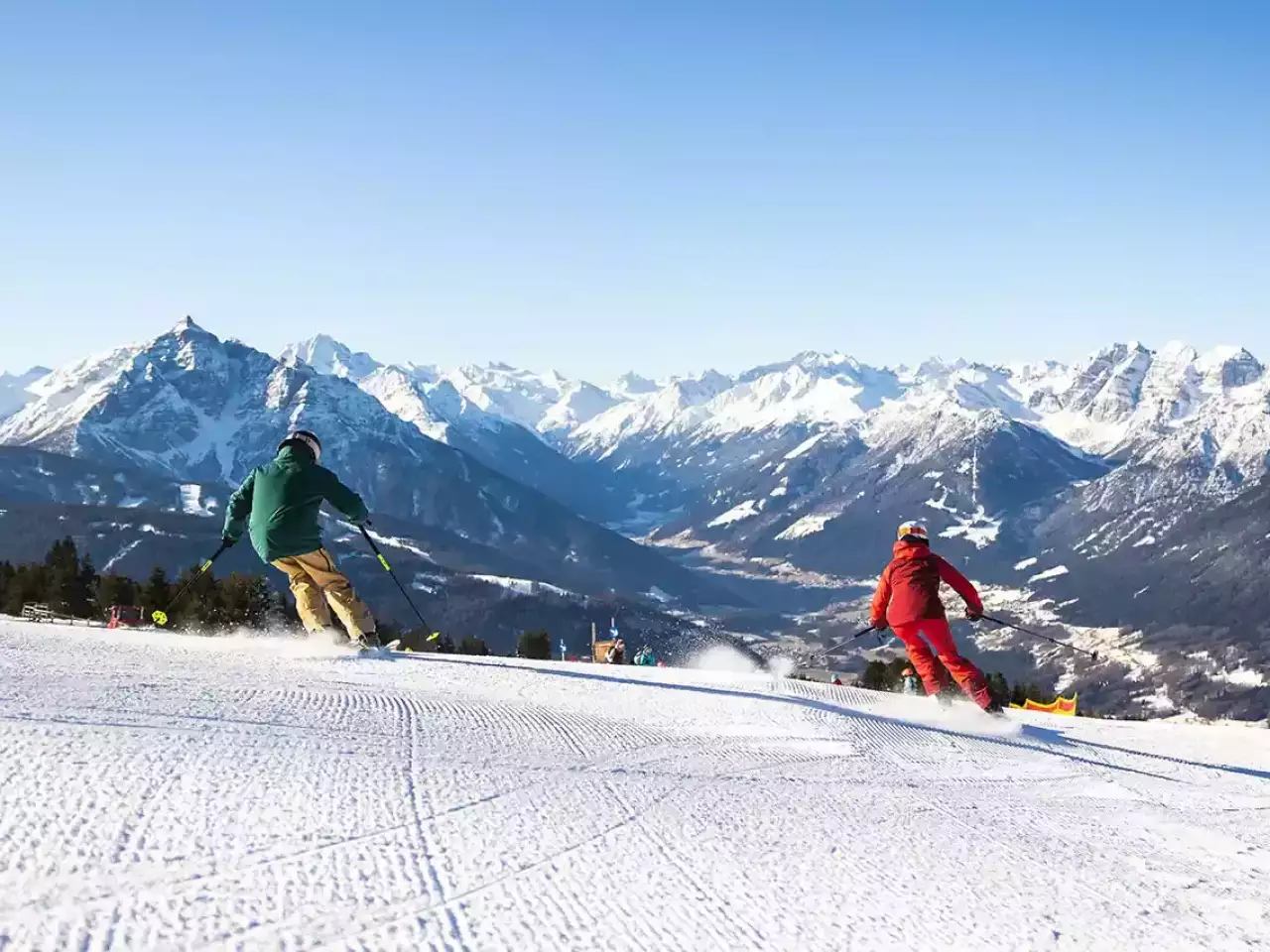 2 Skifahrer carven mit Berge im Hintergrund