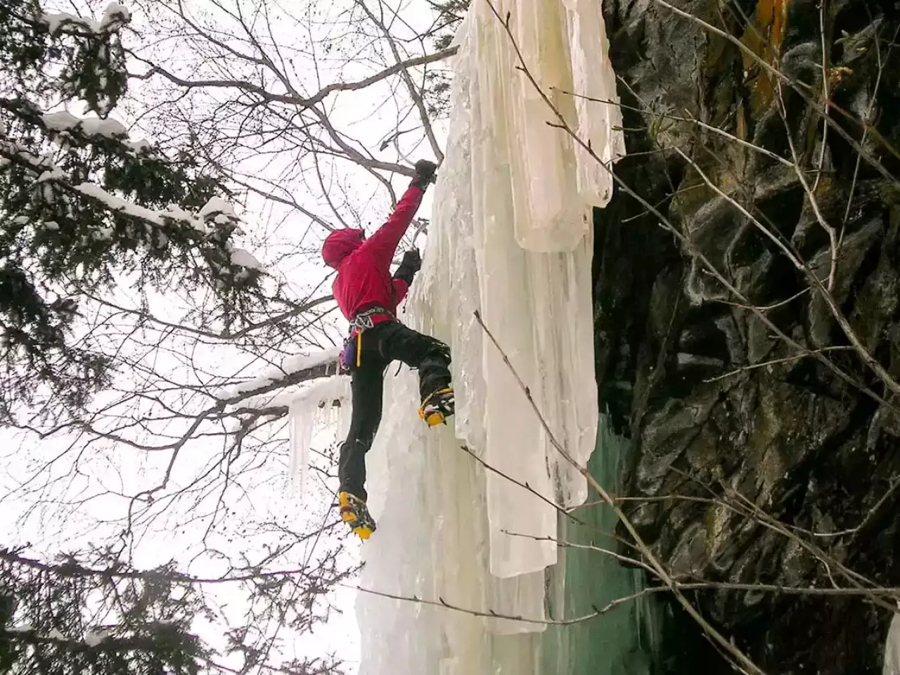 Frau beim Eisklettern am Wasserfall